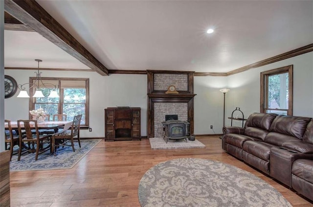 living room with light hardwood / wood-style flooring, a wood stove, beamed ceiling, and a wealth of natural light