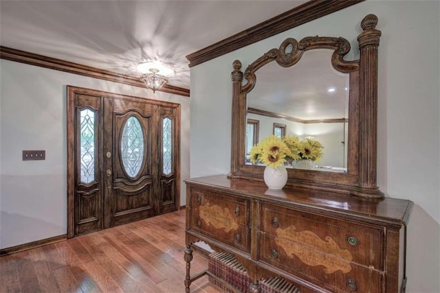 foyer entrance with ornamental molding and light wood-type flooring