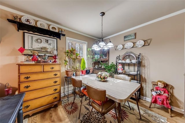 dining room with crown molding, light hardwood / wood-style floors, and a chandelier