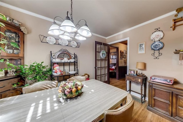 dining space with ornamental molding, a chandelier, and light hardwood / wood-style flooring