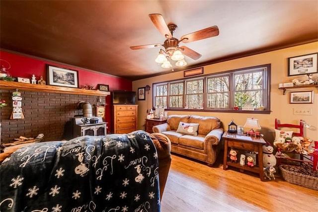 living room with ceiling fan, light hardwood / wood-style floors, and a wood stove