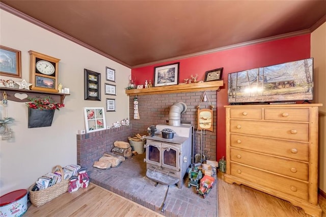 rec room with hardwood / wood-style flooring, ornamental molding, brick wall, and a wood stove