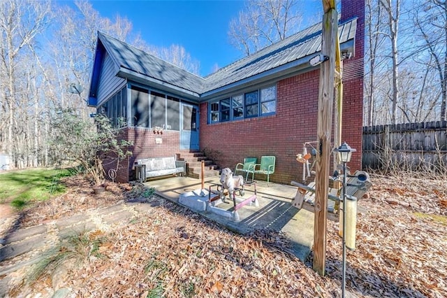 rear view of property featuring a sunroom and a patio