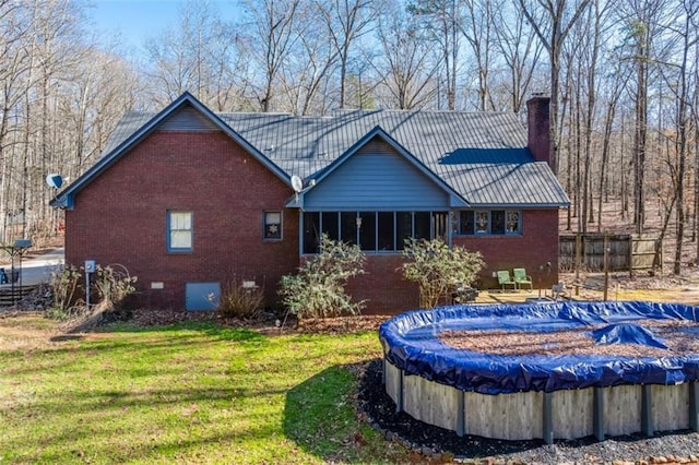 rear view of house with a lawn and a covered pool