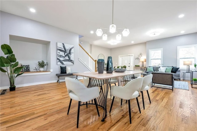 dining space with light hardwood / wood-style floors and an inviting chandelier