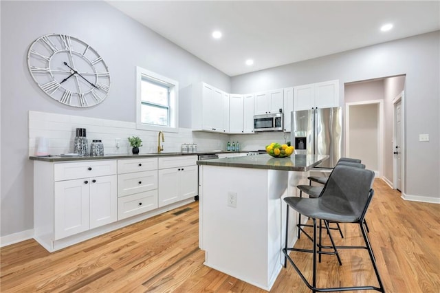 kitchen with a center island, a kitchen bar, white cabinetry, and appliances with stainless steel finishes