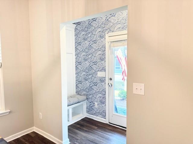 doorway to outside featuring baseboards, wallpapered walls, and dark wood-style floors