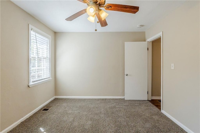 empty room with a ceiling fan, carpet flooring, visible vents, and baseboards