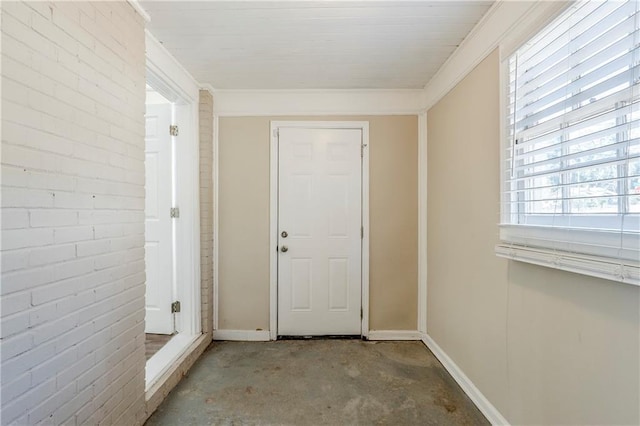 entryway featuring unfinished concrete floors, baseboards, and brick wall