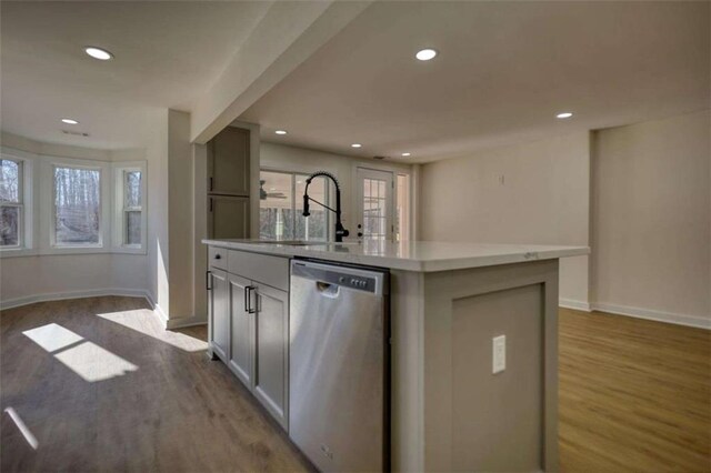 kitchen with white cabinetry, stainless steel dishwasher, an island with sink, and light wood-type flooring