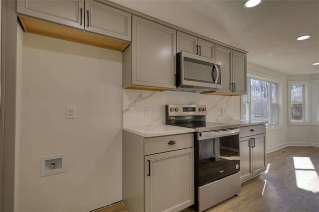 kitchen with light stone countertops, backsplash, and stainless steel appliances