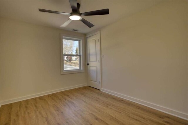 empty room with ceiling fan, electric panel, and light hardwood / wood-style floors