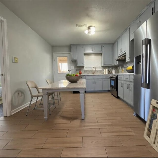 kitchen featuring stainless steel appliances, sink, gray cabinetry, and backsplash