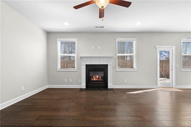 unfurnished living room with recessed lighting, dark wood-type flooring, a fireplace with flush hearth, visible vents, and baseboards