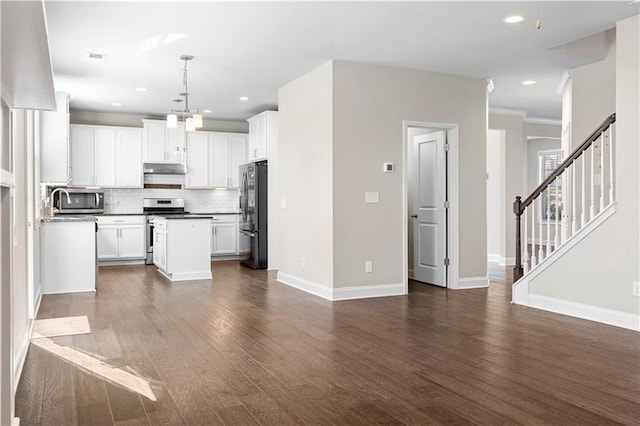 kitchen featuring stainless steel appliances, dark countertops, decorative light fixtures, and white cabinetry