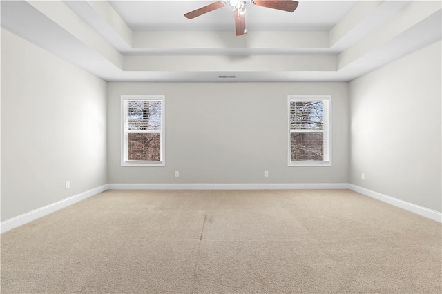 spare room with visible vents, a raised ceiling, a wealth of natural light, and baseboards