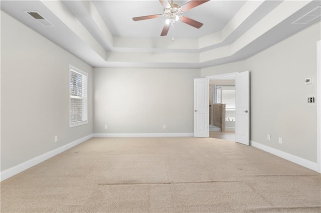 spare room featuring a healthy amount of sunlight, visible vents, and a tray ceiling