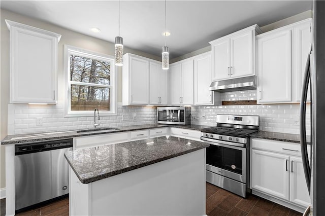 kitchen with under cabinet range hood, a kitchen island, a sink, white cabinetry, and appliances with stainless steel finishes