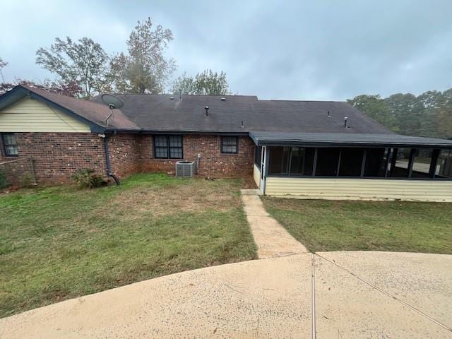 back of house featuring central AC, a sunroom, and a yard