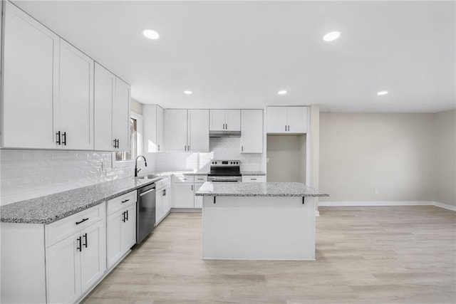 kitchen featuring white cabinetry, light stone counters, a center island, stainless steel appliances, and decorative backsplash