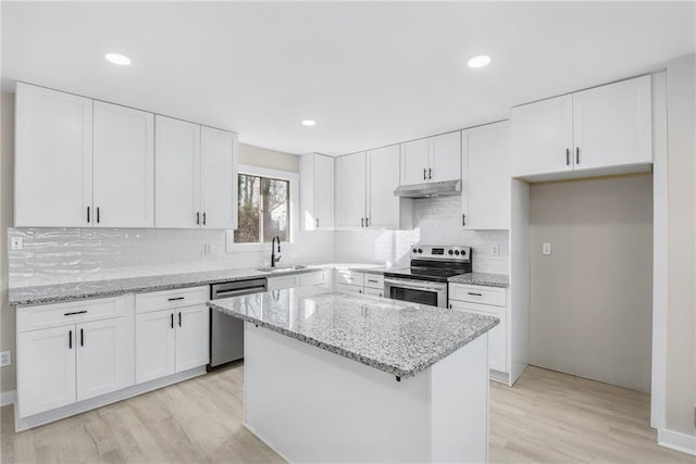 kitchen featuring sink, light stone counters, a center island, appliances with stainless steel finishes, and white cabinets