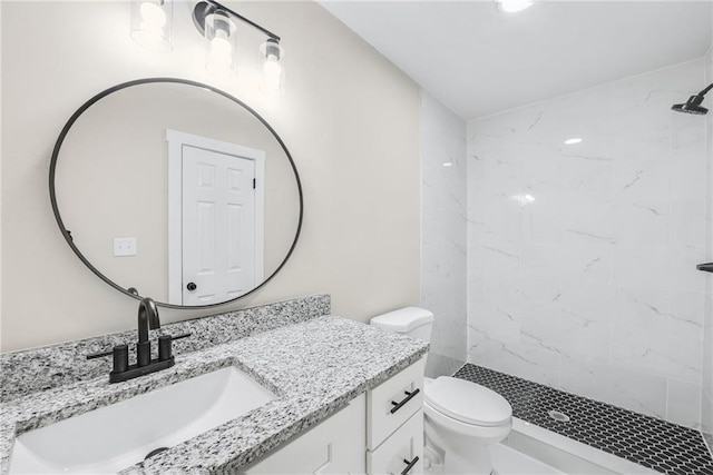 bathroom featuring vanity, tiled shower, and toilet