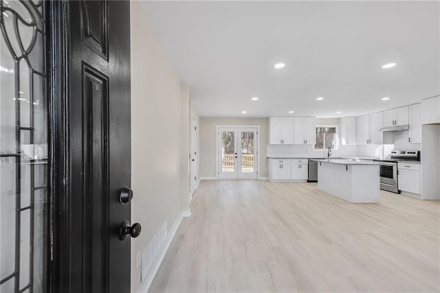 kitchen featuring sink, stainless steel appliances, a center island, white cabinets, and light wood-type flooring