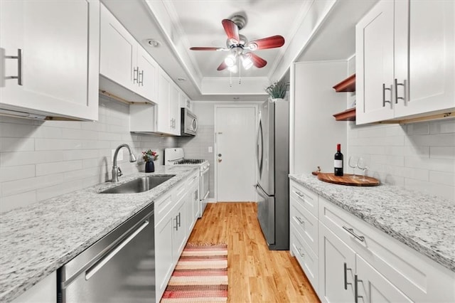 kitchen featuring sink, stainless steel appliances, tasteful backsplash, white cabinets, and light wood-type flooring