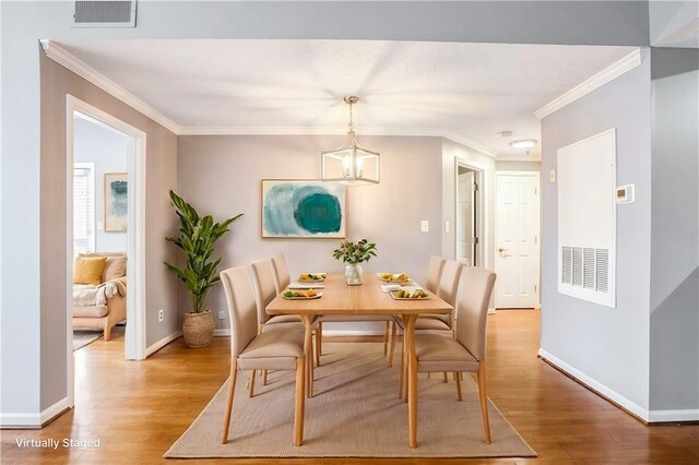 dining area featuring ornamental molding, hardwood / wood-style floors, and a notable chandelier