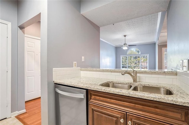 kitchen featuring sink, a textured ceiling, dishwasher, ceiling fan, and light stone countertops