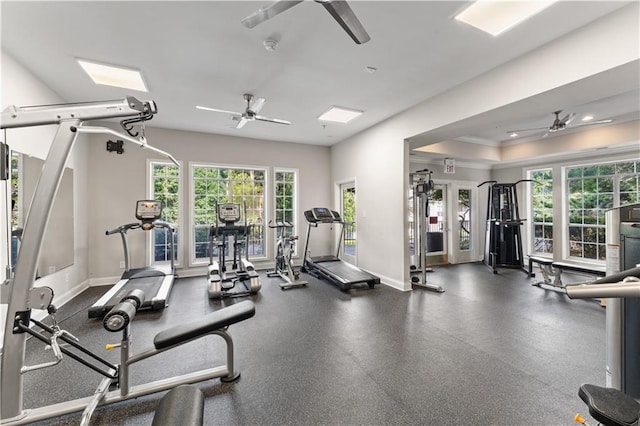 workout area with ceiling fan and a tray ceiling