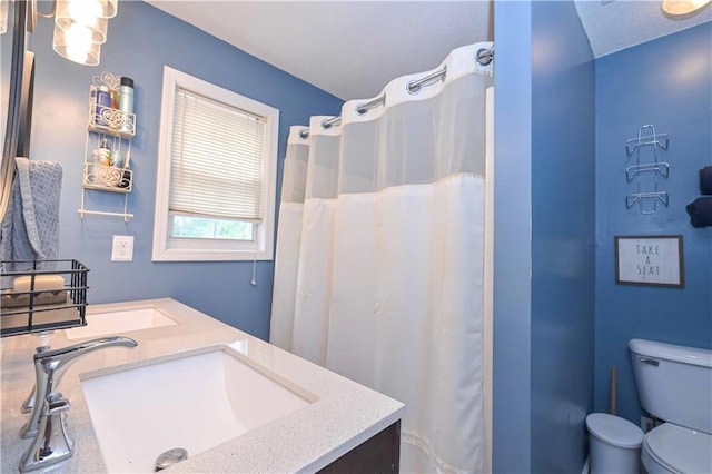 full bath featuring double vanity, a sink, a shower with shower curtain, and toilet