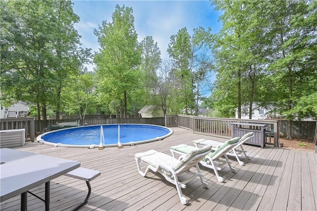 view of swimming pool featuring a fenced in pool, a wooden deck, a fenced backyard, and outdoor dining space