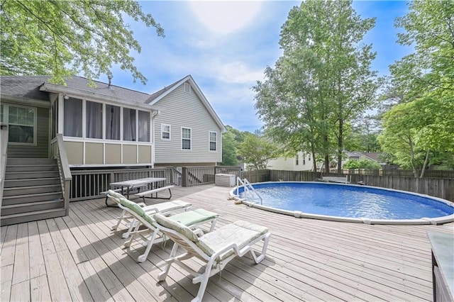 view of swimming pool with a wooden deck, a sunroom, stairway, a fenced backyard, and a fenced in pool