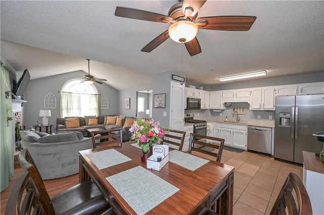 dining room featuring light tile patterned floors, vaulted ceiling, a ceiling fan, and a textured ceiling