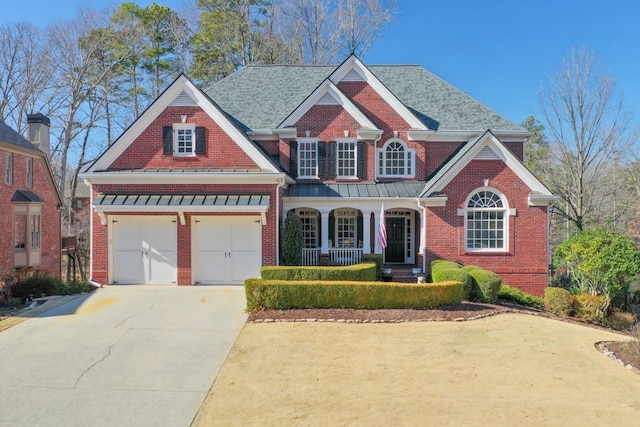 view of front facade featuring covered porch, brick siding, and driveway