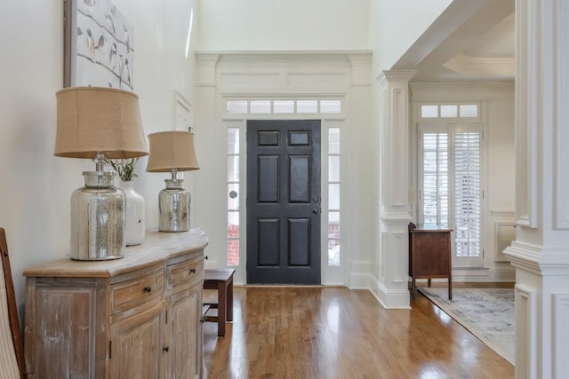 foyer featuring crown molding, ornate columns, and wood finished floors