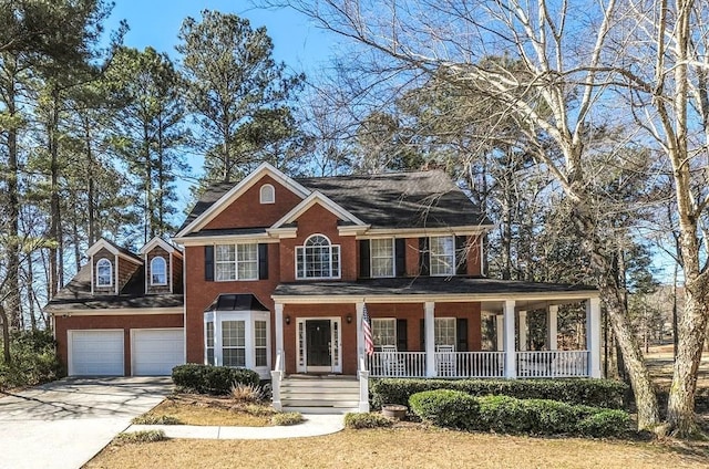 colonial home with covered porch, an attached garage, and concrete driveway