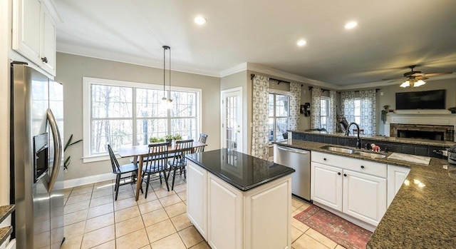 kitchen featuring stainless steel appliances, a sink, white cabinetry, open floor plan, and crown molding