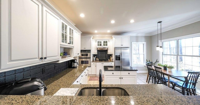 kitchen with white cabinets, a sink, stainless steel appliances, crown molding, and backsplash