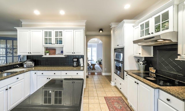 kitchen with arched walkways, crown molding, under cabinet range hood, and black electric cooktop