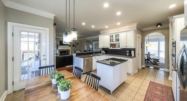 kitchen featuring arched walkways, a fireplace, dark countertops, dishwasher, and a peninsula
