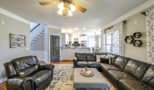 living room featuring ceiling fan, ornamental molding, dark wood-type flooring, and stairway