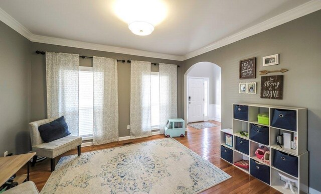 sitting room with baseboards, crown molding, arched walkways, and dark wood-style flooring