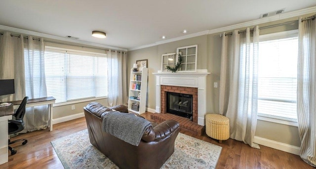 living room featuring visible vents, a fireplace, ornamental molding, and wood finished floors
