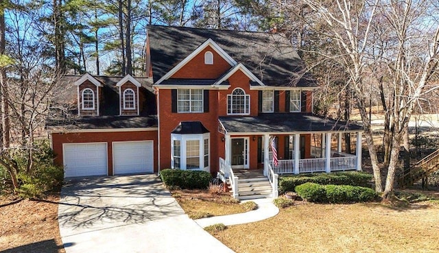 colonial home with covered porch, driveway, and a garage