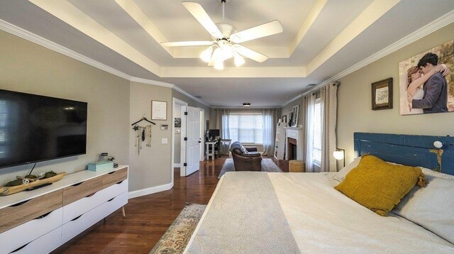 bedroom featuring a fireplace, dark wood finished floors, a raised ceiling, ornamental molding, and baseboards