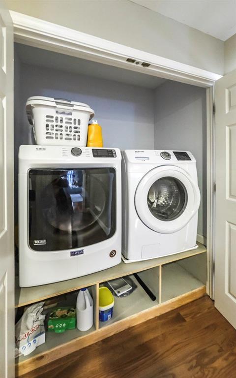 clothes washing area featuring dark wood-style floors, laundry area, and washing machine and dryer