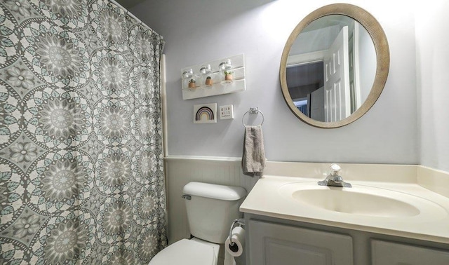 full bathroom featuring toilet, a wainscoted wall, and vanity