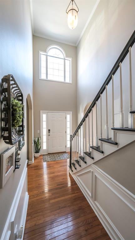 entrance foyer with hardwood / wood-style floors, stairs, and crown molding